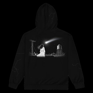 May include: A black hooded sweatshirt featuring a graphic print on the back of a person standing on a rooftop looking at a bright comet in the night sky, with a water tower and antenna nearby. The sleeves and hood feature white constellation patterns.