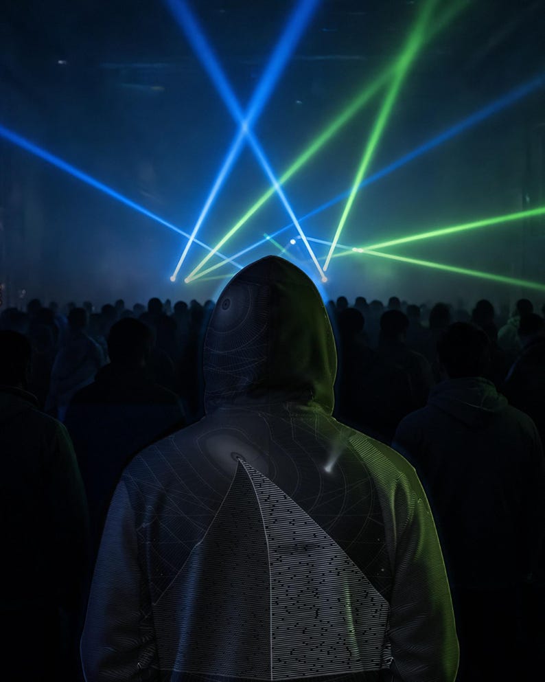 May include: A hooded sweatshirt featuring a graphic print of a pyramid with horizontal lines and circular patterns on the back. The garment is worn in a dark environment illuminated by bright blue and green laser light beams shining from above.