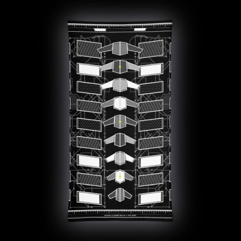 May include: A black neck gaiter featuring a white technical schematic print with geometric shapes, repeating patterns, and small lime green accents. The text JEZERO 77 ASGGE DELTA 17 SOL 0001 is printed in white along the bottom edge of the fabric.