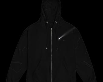 May include: A black zip-up hoodie featuring a silver metal zipper, a drawstring hood, and two front pockets. The chest displays a white graphic of a comet, while the sleeves are decorated with thin, white, linear constellation patterns.