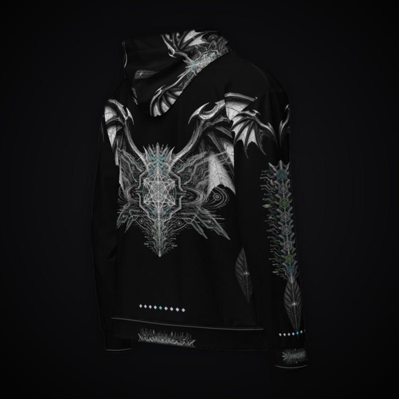 May include: A black hoodie featuring a white graphic print of stylized wings and geometric patterns on the back and hood. The sleeve displays a vertical column of intricate symbols, while a row of small dots is printed above the bottom hem.