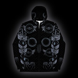 May include: A black zip-up hoodie featuring a repeating pattern of grey winged eyes, circular gear-like motifs, and subtle dotted textures. The garment includes a hood, a full-length front zipper, and long sleeves, with the graphic design covering the entire surface.