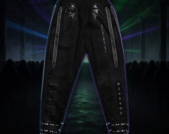 May include: Black joggers featuring a white graphic print of bat wings near the waistband, vertical rows of small white symbols along the legs, a dotted square pattern, and a column of six distinct white icons on the left leg.