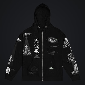 May include: A black zip-up hoodie featuring a white graphic print of extraterrestrial figures, flying saucers, a large eye, and the Japanese characters 周波数. The design includes a QR code on the sleeve and a small geometric symbol on the front.