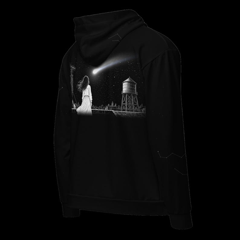 May include: A black hooded sweatshirt featuring a graphic print on the back. The illustration depicts a person standing on a rooftop looking at a comet in the night sky, with a water tower and city skyline visible in the background.