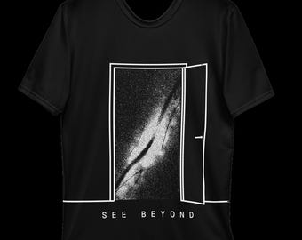 May include: A black short-sleeve t-shirt featuring a white line-art graphic of an open door revealing a starry galaxy inside. Below the door, the text SEE BEYOND is printed in white capital letters. The design is centered on the front.