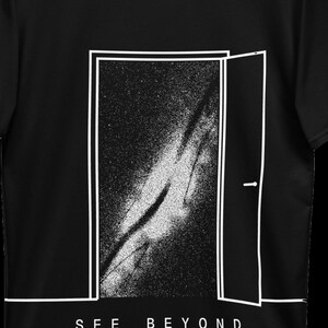 K&ouml;nnte beinhalten: Ein schwarzes T-Shirt mit einer wei&szlig;en Strichgrafik einer offenen T&uuml;r, die eine sternenklare Galaxie zeigt. Unter der T&uuml;r ist der Text SEE BEYOND in wei&szlig;en Gro&szlig;buchstaben gedruckt. Das Design verwendet einen starken Kontrast.