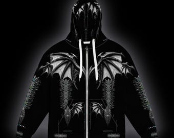 May include: A black zip-up hoodie featuring a white graphic print of large, detailed bat-like wings across the chest and hood. The design includes intricate, symmetrical line work and patterns extending down the sleeves and torso.