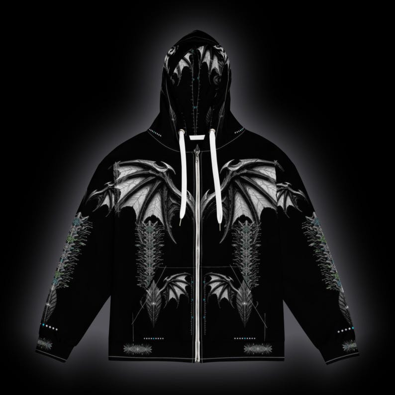 May include: A black zip-up hoodie featuring a white graphic print of large, detailed bat-like wings across the chest and hood. The design includes intricate, symmetrical line work and patterns extending down the sleeves and torso.