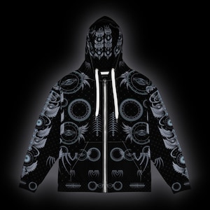 May include: A black zip-up hoodie featuring a repeating pattern of white and light gray graphic elements, including winged eyes, circular gears, and geometric symbols. The garment includes a hood with white drawstrings and a full-length front zipper.