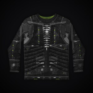 Puede incluir: Una camiseta de manga larga negra con un estampado t&eacute;cnico en blanco y gris. El dise&ntilde;o incluye un gr&aacute;fico central similar a una columna vertebral, patrones de costillas horizontales y sutiles acentos verde ne&oacute;n sobre fondo oscuro.