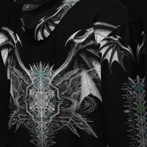 May include: A black long-sleeve hooded sweatshirt featuring a large, intricate white and gray graphic of dragon wings and a geometric star pattern on the back. The design includes detailed mechanical lines and subtle blue accents throughout the print.