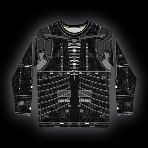 Puede incluir: Una camiseta de manga larga con base negra y un patr&oacute;n t&eacute;cnico de placa de circuito en blanco y verde ne&oacute;n. El dise&ntilde;o incluye l&iacute;neas geom&eacute;tricas, estructuras de rejilla y paneles segmentados que imitan un esquema o una armadura rob&oacute;tica.