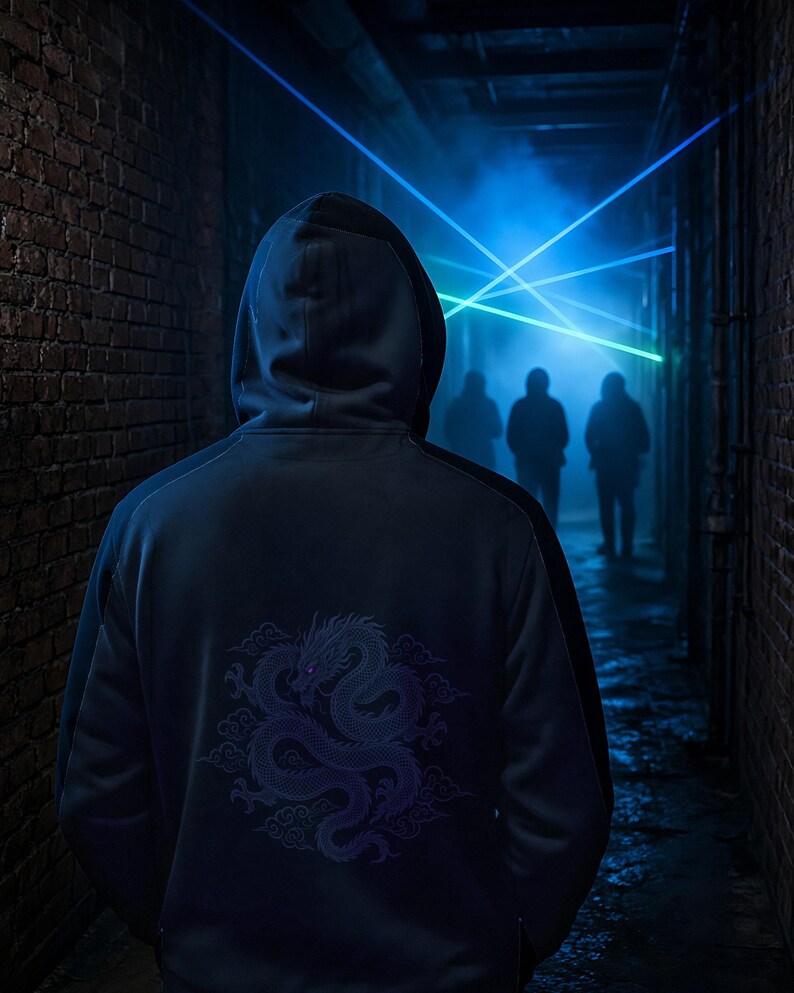 Puede incluir: Una sudadera con capucha de color azul oscuro que presenta un gr&aacute;fico detallado de un drag&oacute;n morado en la espalda. La prenda es usada por una persona de espaldas en un estrecho pasillo de ladrillo iluminado por rayos l&aacute;ser azules y verdes.