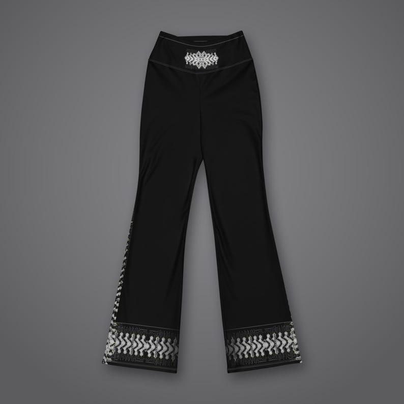 May include: Black high-waisted pants featuring a white geometric pattern at the hem and a matching white decorative emblem centered on the waistband. The pants have a flared leg silhouette with a solid black finish throughout the main body.
