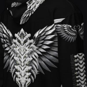 May include: A black hoodie featuring a large, white, mechanical-style wing graphic on the back. The design includes intricate, layered, metallic-looking feathers and a central spine-like structure. A smaller wing motif is visible on the sleeve.