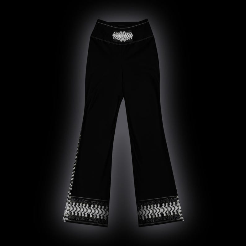 May include: Black high-waisted pants featuring a white geometric pattern at the waistband and a matching white decorative border along the bottom hem of each pant leg. The pants have a straight-leg cut and a solid black fabric construction.
