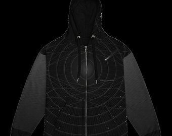 May include: A black zip-up hoodie featuring a white graphic print of concentric circular lines and a shooting star. The design includes a central dark sphere and small scattered dots. The sleeves have a subtle horizontal line pattern.