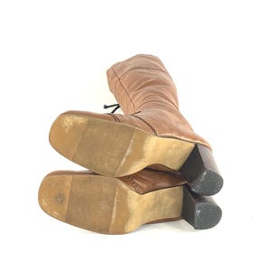Puede incluir: Botas marrones hasta la rodilla con punta cuadrada y tac&oacute;n de bloque. Las botas tienen un dise&ntilde;o con cordones y est&aacute;n hechas de un material texturizado. El tac&oacute;n mide aproximadamente 7.6 cm.