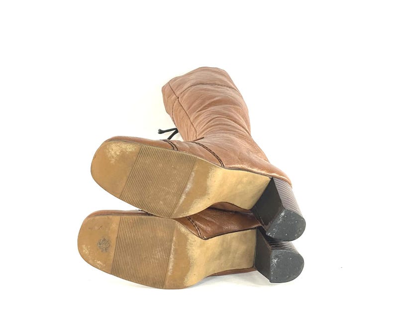 Puede incluir: Botas marrones hasta la rodilla con punta cuadrada y tac&oacute;n de bloque. Las botas tienen un dise&ntilde;o con cordones y est&aacute;n hechas de un material texturizado. El tac&oacute;n mide aproximadamente 7.6 cm.