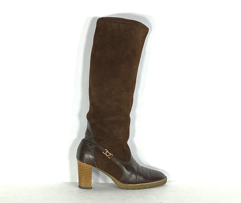 May include: Brown suede knee-high boots with a leather lower section and a wooden heel.