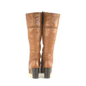 Puede incluir: Un par de botas vintage hasta la rodilla en un tono marr&oacute;n c&aacute;lido. Las botas presentan un aspecto de cuero texturizado, un tac&oacute;n de bloque y cierre de cremallera. Las botas miden unos 38 cm de alto.