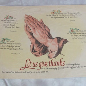 May include: A vintage print with a beige background features a detailed illustration of praying hands. Text in ornate fonts includes phrases like "Let us give thanks" and prayers for various faiths, including Catholic, Orthodox, Jewish, and Protestant.
