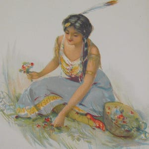 Op de afbeelding: Een vrouw in een blauwe jurk en een kralenvest met een veer in haar haar zit in een bloemenveld. Ze houdt een boeket bloemen in haar hand.