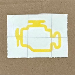 Puede incluir: Una pegatina rectangular blanca que presenta el contorno amarillo de un símbolo de luz de avería del motor. El gráfico representa la forma estilizada de un bloque de motor de combustión interna con una pequeña tapa arriba, centrado en un fondo blanco.