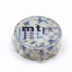 May include: A roll of decorative washi tape with a floral pattern in blue and cream. The tape is wrapped in clear plastic and features the text "mt" and "KAMOIPAPER WASHI ADHESIVE TAPE".