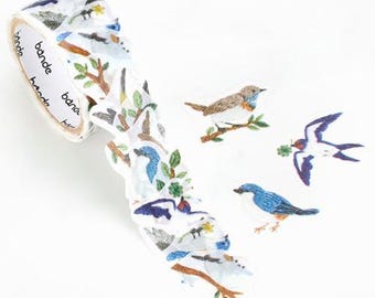 May include: A roll of decorative washi tape featuring a design of birds, branches, and leaves. The tape is white with the brand name "bande" printed on the side. Several bird stickers are also visible.