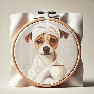 Könnte beinhalten: Ein weißer Hund, der ein weißes Handtuch auf dem Kopf und einen weißen Bademantel trägt, hält eine weiße Tasse mit einer braunen Flüssigkeit darin. Der Hund sitzt auf einem weißen Stoffhintergrund.