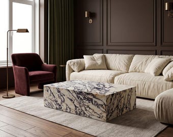 May include: A rectangular coffee table featuring a white and dark purple marble pattern. The table is positioned in a room with a cream-colored sofa, a dark red armchair, a floor lamp, and dark brown paneled walls.