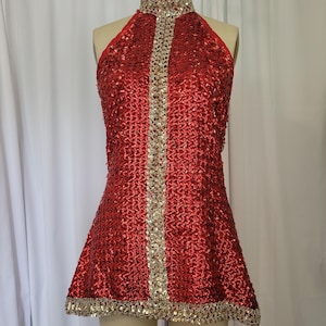 May include: A sleeveless red sequin dress featuring a high mock neck collar and a vertical center panel of gold sequins. The garment includes a gold sequin trim along the hemline and the collar, creating a distinct contrast against the red fabric.