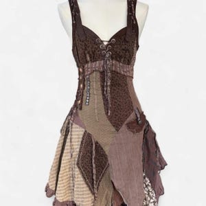 May include: A brown sleeveless dress featuring a patchwork design with various patterns including leopard print, stripes, and floral motifs. The bodice includes a lace-up front with metal eyelets, while the skirt has an asymmetrical hemline.