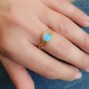 Op de afbeelding: Een gouden ring met een blauwe opaal-edelsteen gezet in een delicaat filigraan ontwerp.