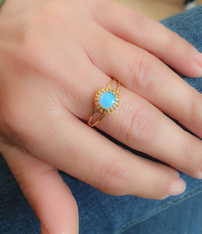 Op de afbeelding: Een gouden ring met een blauwe opaal-edelsteen gezet in een delicaat filigraan ontwerp.