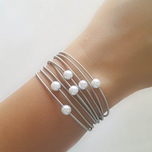 Könnte beinhalten: Ein silbernes Armband mit mehreren Strängen und weißen Perlenakzenten.
