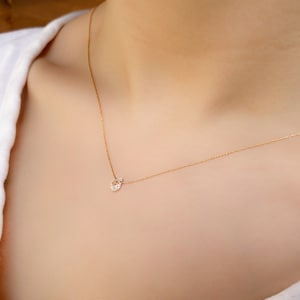 Puede incluir: Un delicado collar de cadena de oro con un pequeño colgante de piedra preciosa transparente.