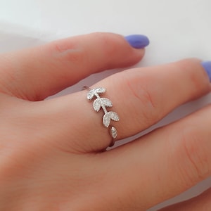 May include: A silver ring with a delicate design of leaves set with small clear stones.