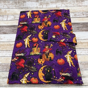 May include: A rectangular fabric cover featuring a purple background with a repeating Halloween pattern of witches on broomsticks, black cats, orange pumpkins, yellow crescent moons with owl faces, and children in clown costumes with yellow stars.