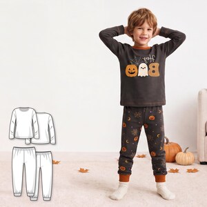 May include: A dark gray long-sleeve pajama set featuring a graphic print of a pumpkin, a ghost, and the text "Hey BOO" on the shirt. The pants have an all-over pattern of small pumpkins, moons, and spiderwebs with orange cuffs.