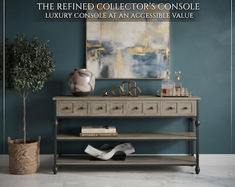 Op de afbeelding: Een console-tafel van licht hout met een donker metalen frame, vier lades met ronde knoppen en twee open planken. De tekst luidt: THE REFINED COLLECTOR'S CONSOLE, LUXURY CONSOLE AT AN ACCESSIBLE VALUE. Het bevat een vaas, decor en een glazen dienblad.