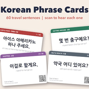 May include: A set of Korean Phrase Cards featuring 60 travel sentences. Four rectangular cards are displayed, each with a colored header, Korean text, romanization, and a QR code. The headers are labeled Cafe & Food, Getting Around, Shopping, and Help & Health.