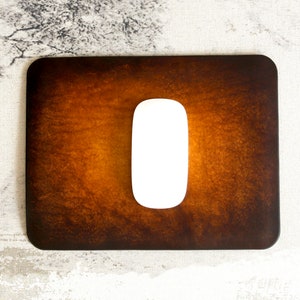 May include: A brown leather mouse mat with a white mouse on top. The mouse mat has a distressed, vintage look.