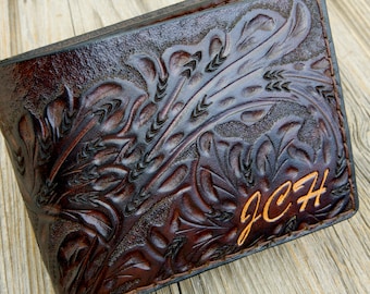 May include: A brown leather wallet with an intricate floral design embossed into the surface. The wallet has the initials "J.C.H." embossed in gold lettering.
