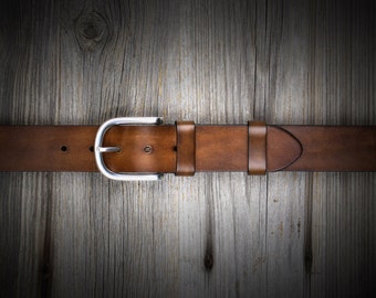 May include: A brown leather belt with a silver buckle. The belt is on a wooden background.
