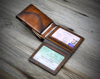 May include: A brown leather wallet with multiple card slots and a clear ID window. The wallet is open and folded in half, revealing the interior.