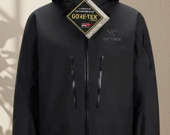 May include: A black hooded jacket featuring a full-length front zipper, two vertical zippered chest pockets, and a small zippered pocket on the left sleeve. The Arc'teryx logo is embroidered on the chest, and a Gore-Tex tag is attached.