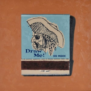 May include: A vintage matchbook cover with a blue background and a black and white illustration of a pirate with an eyepatch and a hat. The text "Draw Me!" is printed in black and white on the cover. The text "See Inside" is printed in black on the cover.